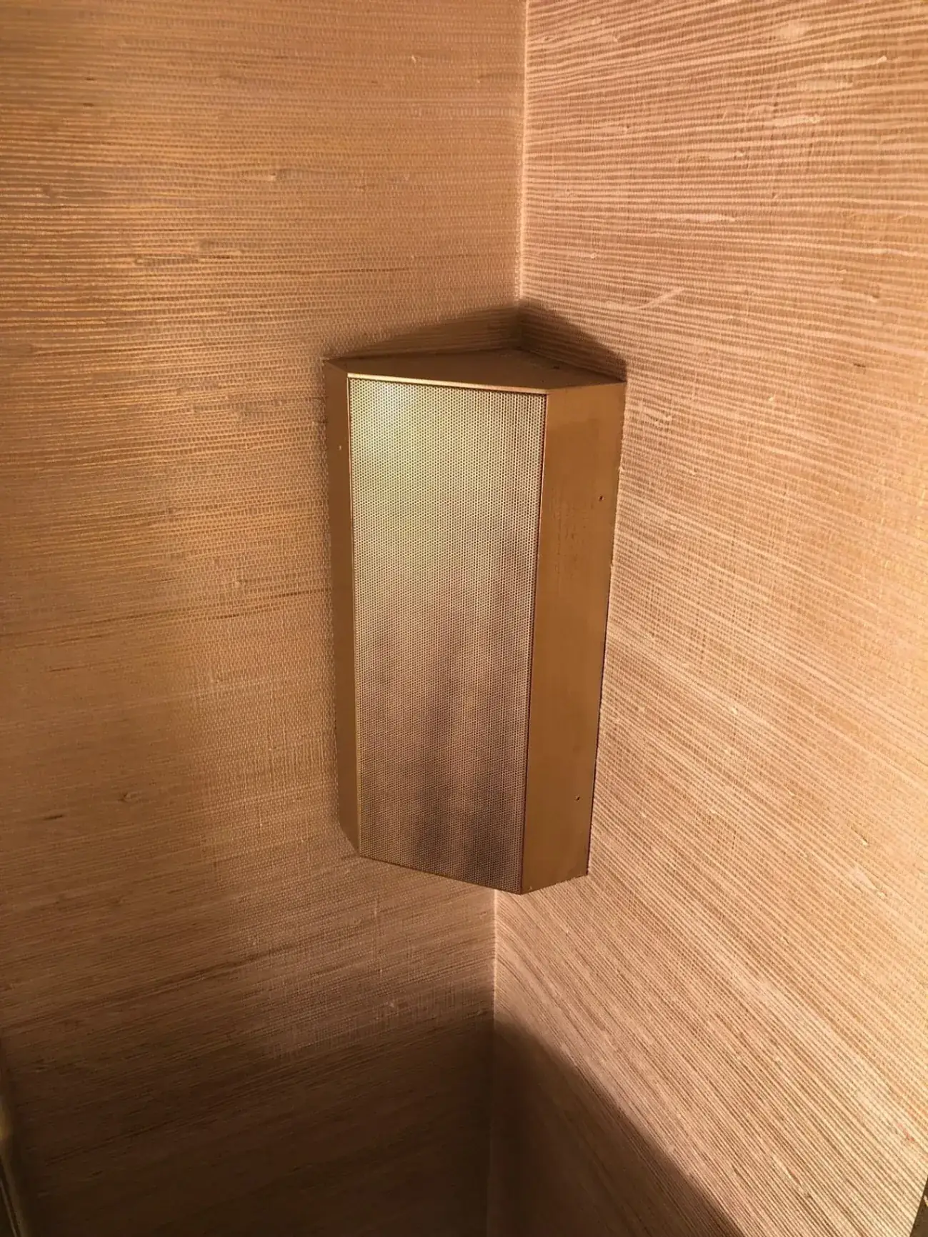 Corner-mounted hidden speaker matching wall texture